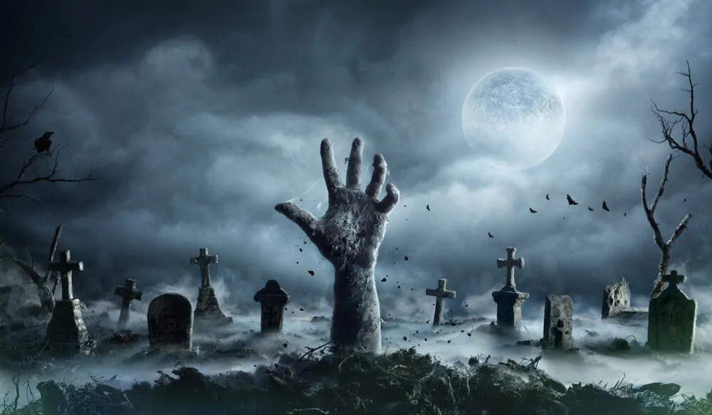 Mano di zombie che si alza da un cimitero in una notte spettrale